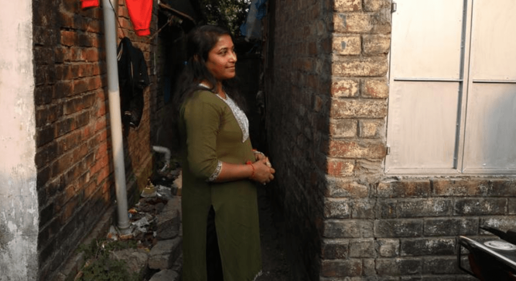 Woman standing calmly in narrow alley, symbolizing quiet confidence without noise