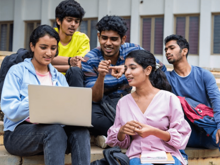 Group of Indian college students discussing together around laptop sharing motivation and success energy